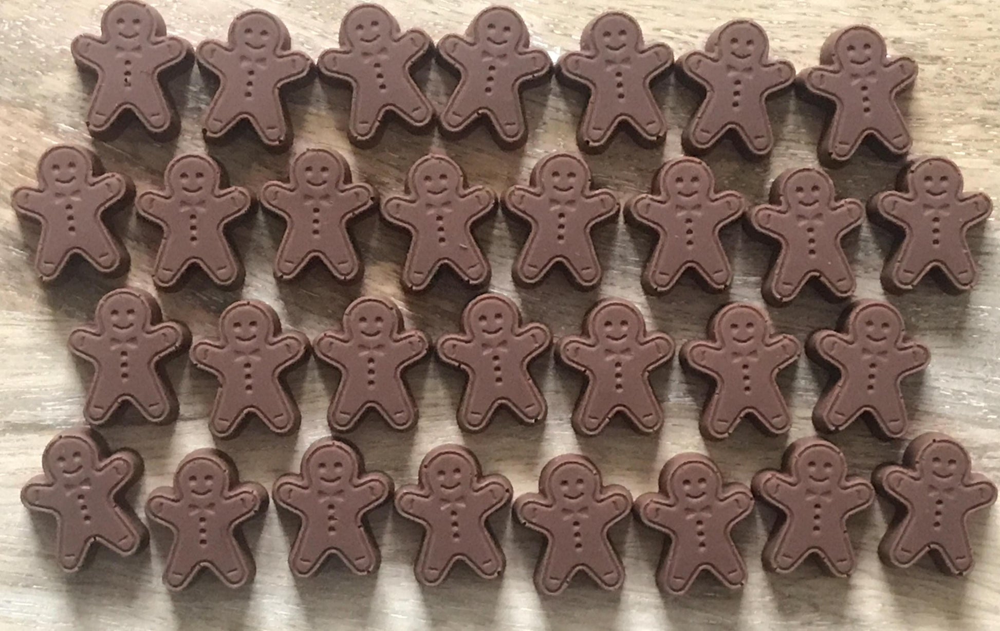 Multiple chocolate gingerbread men on a wooden surface